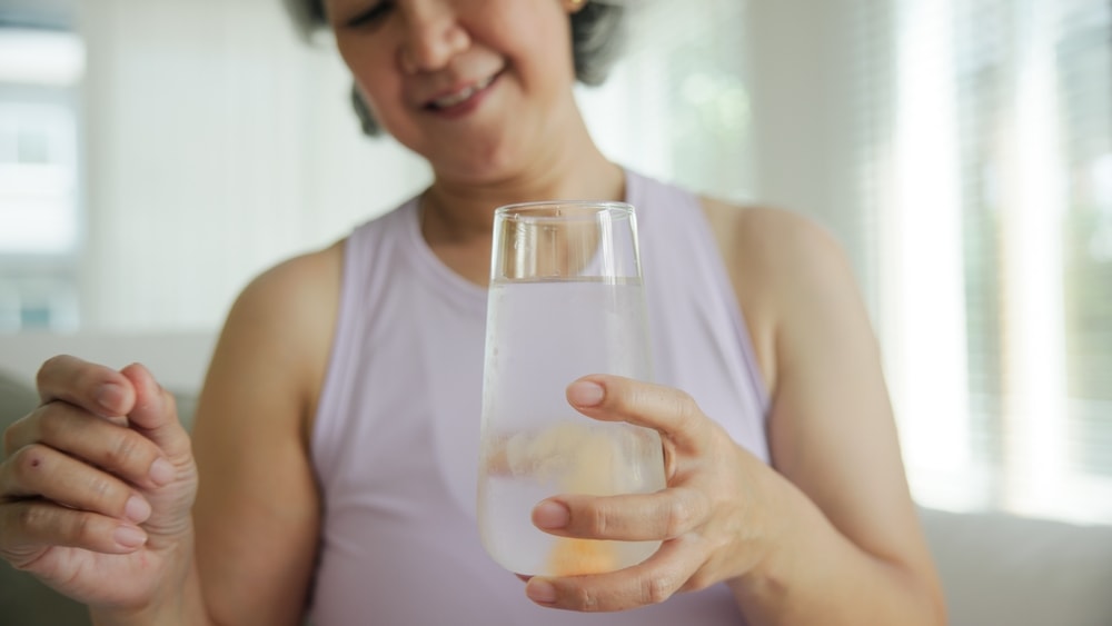 donna beve un bicchiere di sali minerali