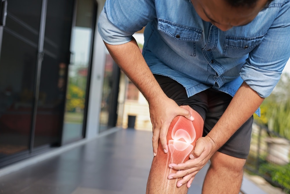 uomo si tiene il ginocchio con entesite